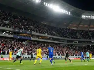 Sân vận động bóng đá đông đúc khán giả cuồng nhiệt cổ vũ trận đấu kịch tính dưới ánh sáng floodlight rực rỡ, hình ảnh cá cược thể thao sunwin 2026 mới nhất